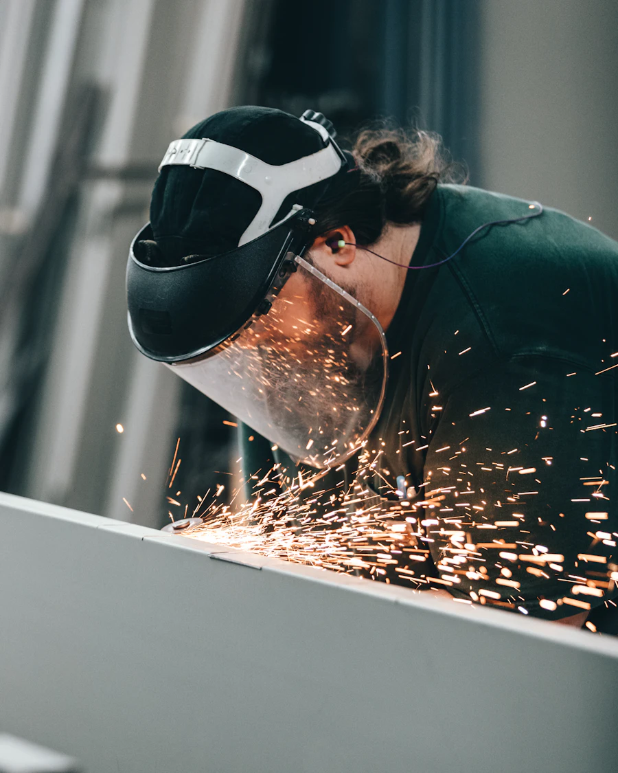 A welder in a helmet, sparks streaming from the seam being worked.